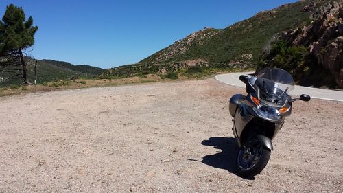 Motorcycle parked on field against clear blue sky