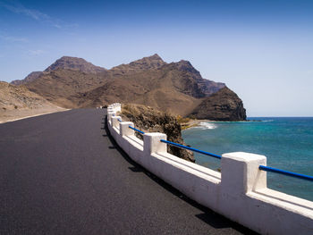 Scenic view of sea and mountains against clear blue sky