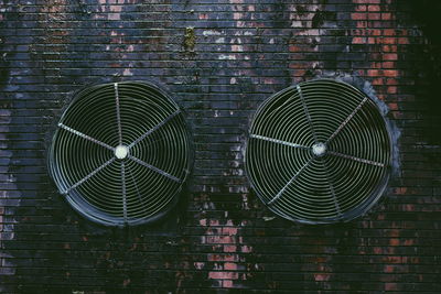 Close-up of electric fan on brick wall