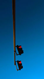 Low angle view of road sign against clear blue sky