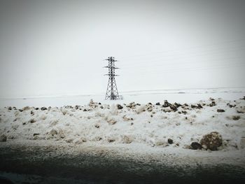 Electricity pylon against clear sky during winter