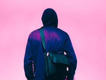 Rear view of man standing against pink background