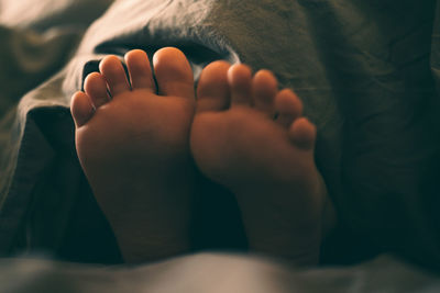 Bare children's feet stick out from under the blanket. 