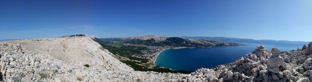 Panoramic view of sea and mountains against blue sky