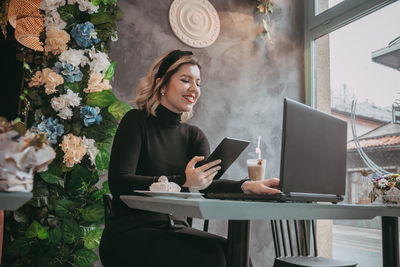 Woman using phone while sitting on table