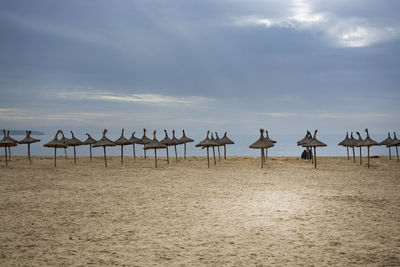 Deck chairs on beach against sky