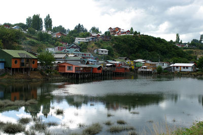 Houses by lake and town against sky