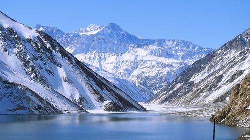 Scenic view of lake by snowcapped mountains against sky