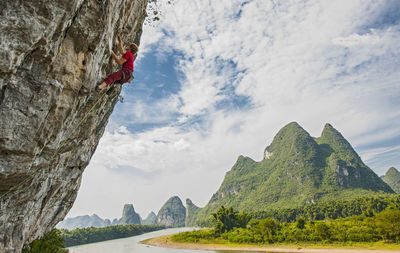 Young man climbing steep rock face in yangshuo / china