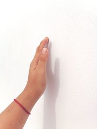 Close-up of hand against white wall