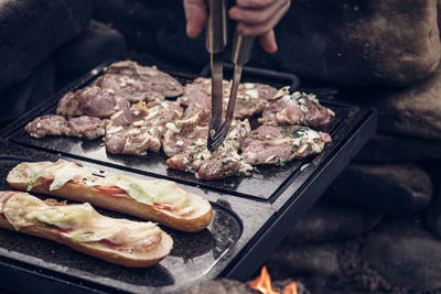 Man prepares a juicy pork neck with basil and barbecue spices and a baguette with tomato cheese 