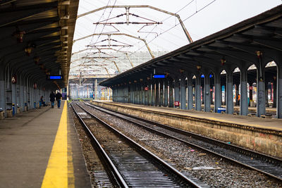 People waiting at railroad station platform against sky