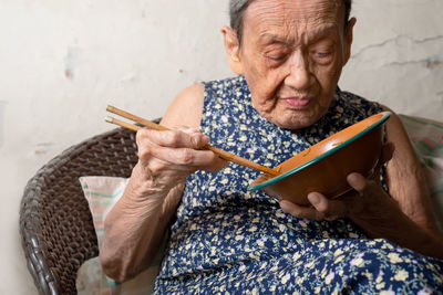 Senior woman having meal from bowl at home