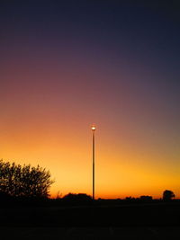 Silhouette street light against clear sky at sunset