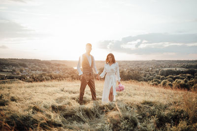 Couple kissing on field against sky