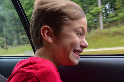 Happy boy looking through window of speeding car