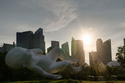 Statue of modern buildings in city against sky