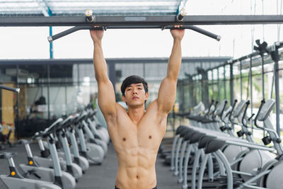 Portrait shirtless man exercising at gym