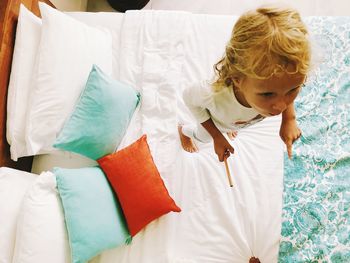 Directly above shot of girl standing on bed at home