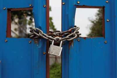 Close-up of locked blue metal gate