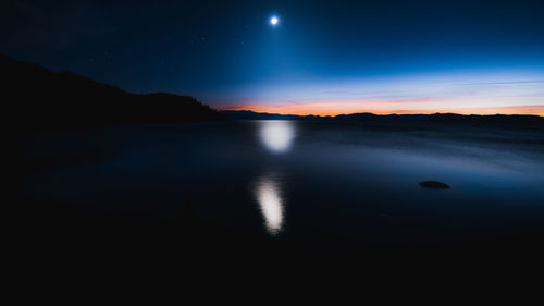 Scenic view of lake against sky at night