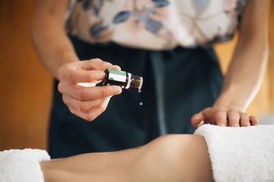 Ayurvedic therapist dropping ayurveda essential oil on female patient stomach