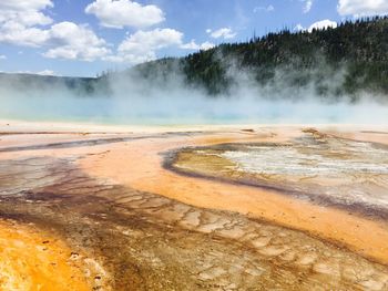 Geyser at yellowstone national park against sky on sunny day