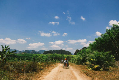 Dirt road on field against sky