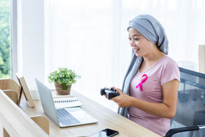 Young woman using phone while sitting on table
