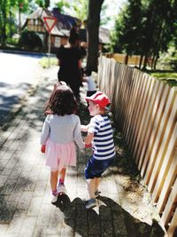 Siblings walking on sidewalk in city