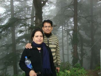 Portrait of young man standing against trees in forest