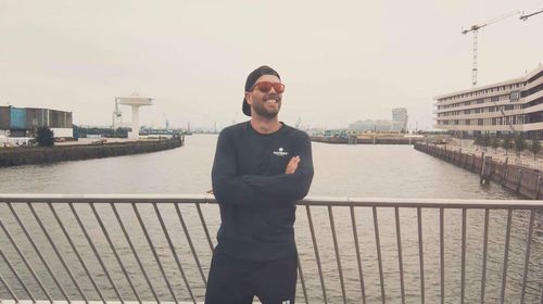 Man standing on bridge over river in city against sky