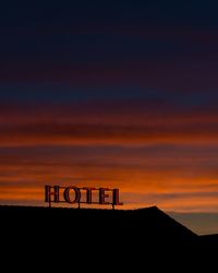 Hotel text against sky at sunset