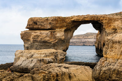 Rock formations by sea against sky