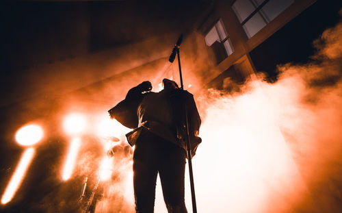 Rear view of silhouette man standing against orange sky