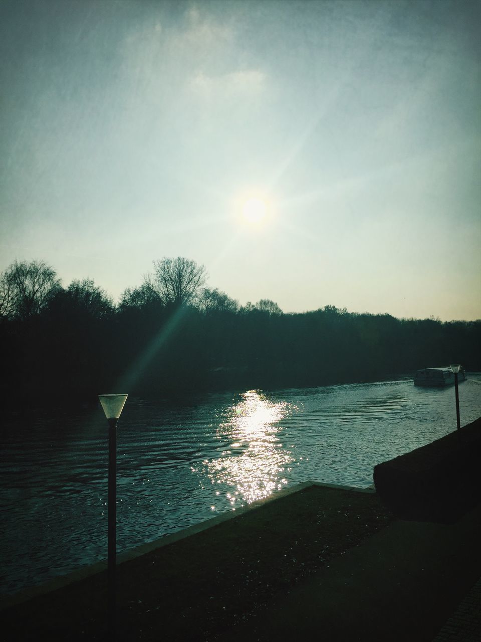 water, sun, sky, tranquil scene, tranquility, reflection, lake, sunset, sunlight, silhouette, scenics, beauty in nature, nature, sunbeam, lens flare, river, tree, idyllic, cloud - sky, outdoors