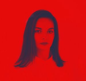 Portrait of young woman against red background