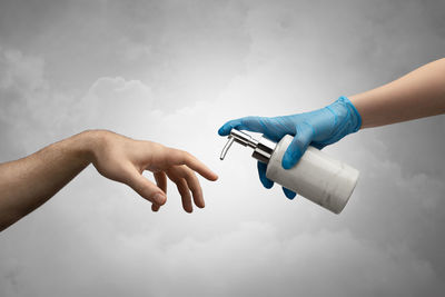 Close-up of hands holding camera against sky