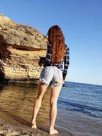 Woman standing in water against clear sky