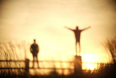 Silhouette man with arms outstretched at beach during sunset