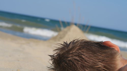 Midsection of man at beach against sky