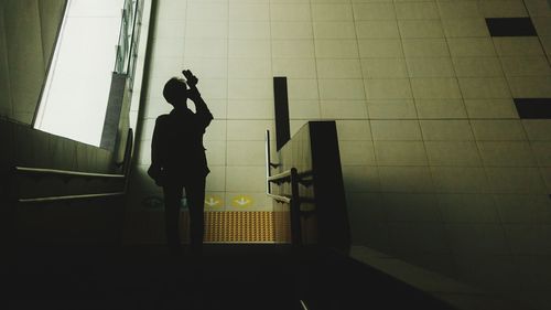 Silhouette man standing by window at subway station