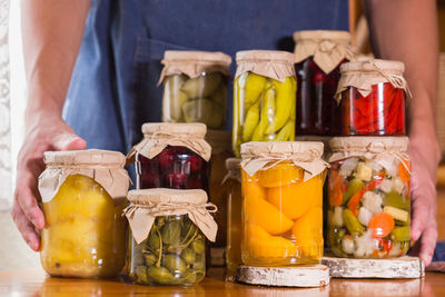 Close-up of hand holding glass jar on table