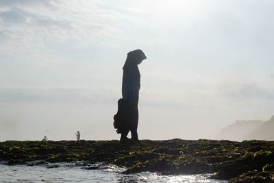 Man standing on sea shore against sky