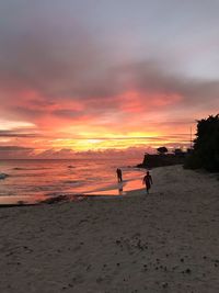 Silhouette people standing on beach against sky during sunset