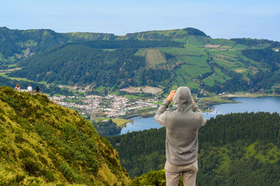 Rear view of man looking at mountains against sky