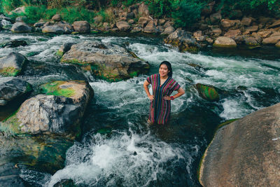 Full length of man standing on rock by river