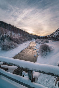 River in winter with snow, sunset and light reflection on water