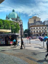 People walking on street against buildings in city