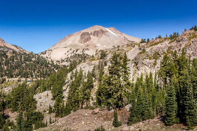 Panoramic view of trees and mountains against blue sky